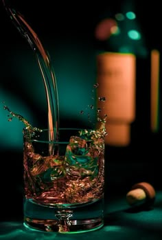 a glass filled with liquid next to a bottle and some corks on a table