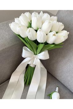 a bouquet of white tulips tied to a gray couch with a white ribbon