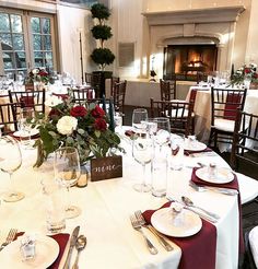 a dining room set up with white table cloths and red place settings for dinner