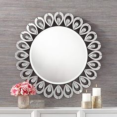 a white dresser topped with a mirror next to a vase filled with flowers and candles