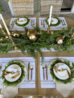 the table is set with gold and white plates, silverware, greenery, and candlesticks