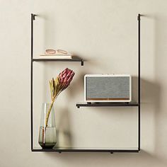 a vase with a flower and a radio on a shelf next to a wall mounted speaker