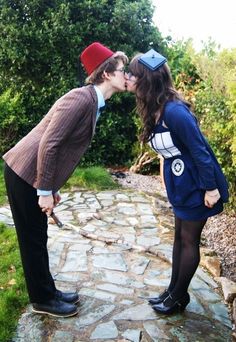 two people are kissing each other on the stone path in front of some bushes and trees