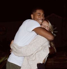 two people hugging each other outside at night