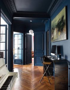 an empty room with a piano, desk and chair in it's center area