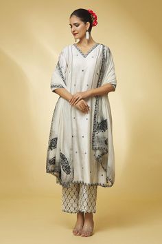 Ivory chanderi silk A-line kurta with bell sleeves, wave, geometric pattern contrast resham and thread embroidery. Paired with straight fit pant with checkered hand block print and handloom chanderi embroidered dupatta with scalloped cut work border.
Components: 3
Pattern: Embroidered and Printed
Type Of Work: Mirror, Resham Work and Hand Block Print
Neckline: V Neck
Sleeve Type: Bell Sleeves
Fabric: Chanderi Silk, Dupatta: Handloom Chanderi
Color: Ivory
Other Details: 
Scalloped embroidered cut V Neck Kurta, Punit Balana, Printed Mirror, Resham Work, Kurta Set For Women, A Line Kurta, Straight Fit Pants, Embroidered Dupatta, Casual Day Outfits