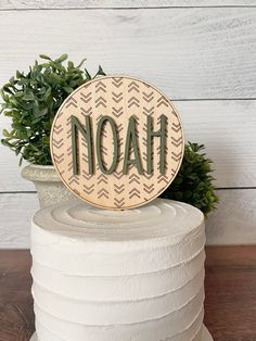 a wooden sign that says noah on top of a stack of white paper towels next to a potted plant