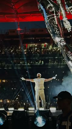 a man standing on top of a stage with his arms wide open in front of an audience