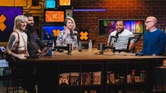 four people sitting at a table with microphones in front of them on the show