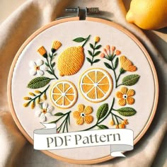 an embroidery pattern with oranges and flowers on it, next to two lemons