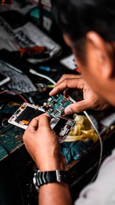 a man working on an electronic device with multiple wires and components around him, including the motherboard