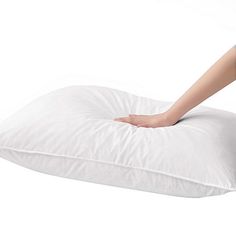 a woman is laying on a white pillow with her hand on the pillow and it's cover