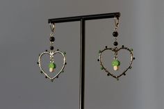 These y2k hoop earrings feature a wire wrapped heart hoop, green and black glass beads, and a green mushroom charm. This pair blends alt style with vibrant green accents, creating truly one-of-a-kind earrings!  ** Limited quantity, only 3 available. DETAILS * Dimensions: ~2.7in L x ~1.4in W * Weight (both): ~.25oz  * Clay mushroom beads, glass beads, acrylic beads * 100% brass findings and lever back -- Nickel-free & hypoallergenic! -- Jewelry findings and metal components are gently cleaned, applied with an anti-tarnish shield, and delicately polished. HIGHLIGHTS The highlight of these y2k-inspired earrings is an adorable green mushroom bead, accented by black and green glass beads wrapped around the hoop. These unique pre-loved candy beads were crafted in the early 2000s. BEADS:  8-9 x 9 Wire Heart Earrings, Earrings Grunge, Mushroom Beads, Grunge Earrings, Candy Beads, Earrings Y2k, Y2k Earrings, Green Mushroom, Clay Mushroom