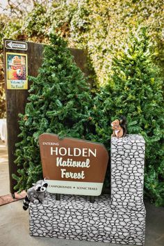 a sign for the national forest in front of some bushes and trees with stuffed animals on it