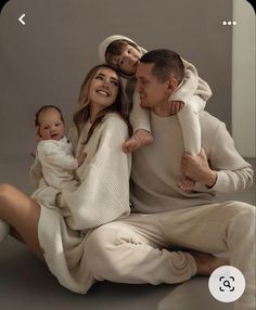 a man, woman and baby are sitting on the floor with their arms around each other