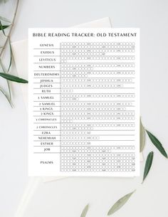 the printable bible reading tracker is on top of a white table with green leaves