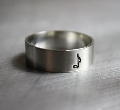 a silver ring with a musical note engraved on the side, sitting on a table