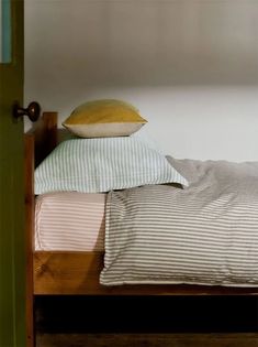 a bed with three pillows on top of it next to a green door in a room