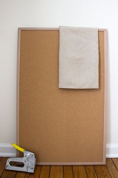 a cork board with a piece of cloth on it next to a pair of pliers