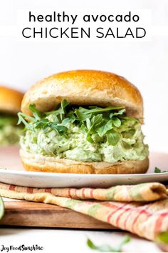 a close up of a sandwich on a plate with avocado in the background