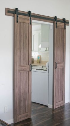 an open door leading to a kitchen with white appliances in the background and wood flooring