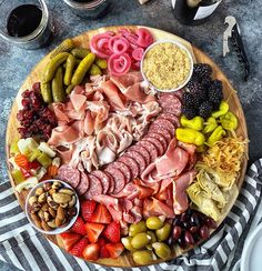 a platter filled with meats, fruit and vegetables