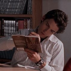 a man sitting at a desk reading a book