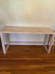 a wooden table sitting on top of a hard wood floor next to a white wall