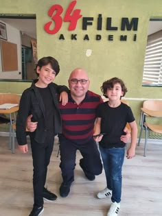 two boys and an older man standing in front of a sign that says 34 film akademi