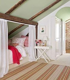 an attic bedroom with exposed beams and white curtains