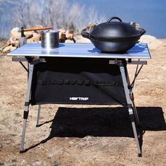 an outdoor table with a pot and pan on it