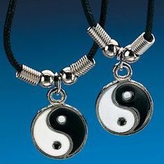 two black and white yin - yang pendants are hanging from a necklace on a cord