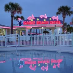 the magic beach motel is lit up with pink neon lights and palm trees around it