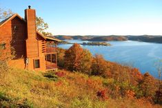 a log cabin sits on top of a hill overlooking the lake