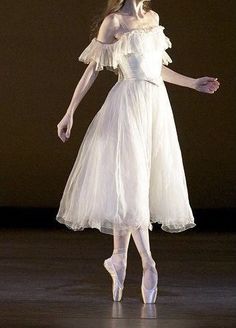 a woman in a white dress standing on a stage with her arms out and legs spread wide