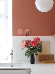 a vase filled with pink flowers sitting on top of a counter next to a sink