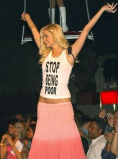 a woman standing on top of a stage with her arms in the air and hands up