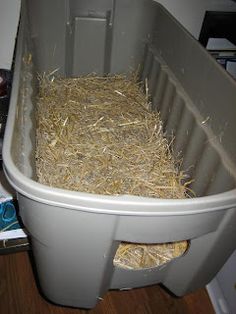 a plastic container filled with hay on top of a wooden floor