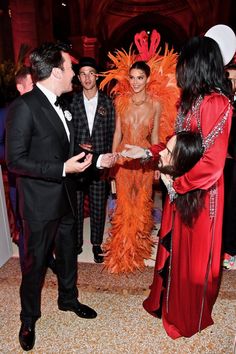 a man in a tuxedo is shaking hands with two other people at an event