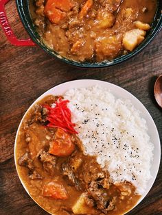 two plates filled with rice and meat next to a pot of stew on a wooden table