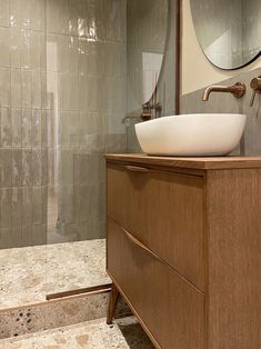 a bathroom sink sitting on top of a wooden cabinet next to a walk in shower