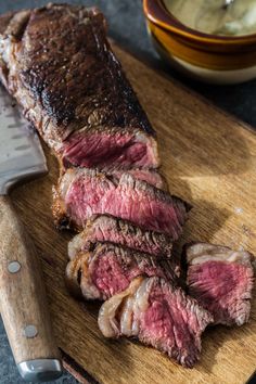 steak sliced up on a cutting board next to a knife