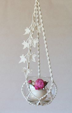 a flower pot hanging from a rope with flowers in the vase on it's side