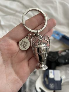 a person holding a silver trophy keychain in their hand