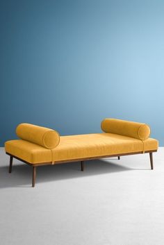 a yellow couch sitting on top of a white floor next to a blue wall in an empty room