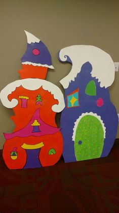 two cardboard cutouts of houses with hats on top and one has a green door