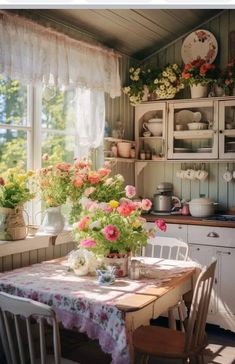 a table with flowers in vases on top of it next to a kitchen window