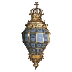 an ornately decorated hanging light fixture with blue glass panels and gold trimmings