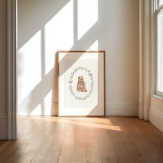 a framed photograph sitting on top of a hard wood floor next to a window with sunlight streaming through it