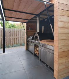 an outdoor bbq with grill and oven in the middle of a patio area that is made out of wood planks